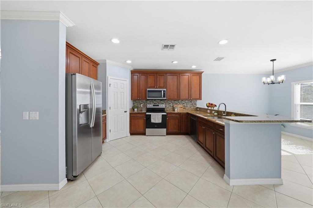 Kitchen featuring wood cabinetry, stainless steel appliances, speckled countertops, and a tile backsplash