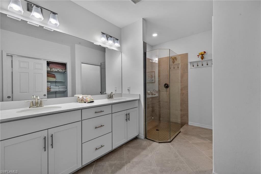 Bathroom featuring a dual vanity with white cabinetry and chrome hardware, a large mirror, and overhead vanity lighting