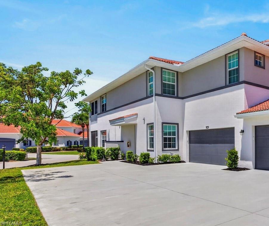 Stucco-finish exterior featuring a tile roof, an integrated two-car garage, and a concrete driveway