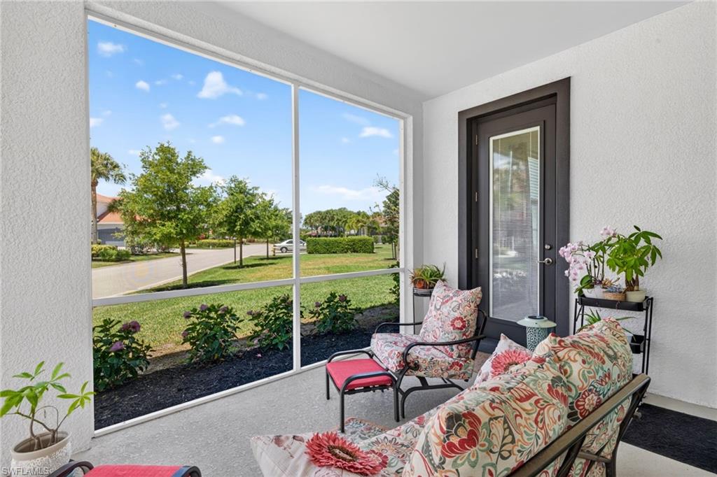 Screened porch featuring a textured stucco exterior, a dark-framed door with a clear glass panel, and a concrete floor