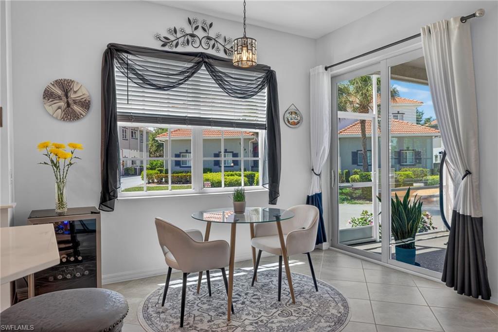 Bright dining area with large windows, sliding glass door access, tiled flooring, and a built-in beverage cooler