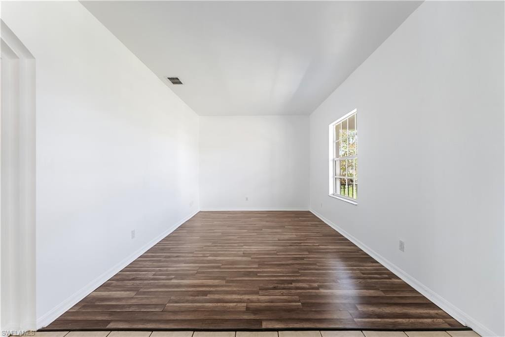 Spacious room featuring wood-finish flooring and neutral white walls