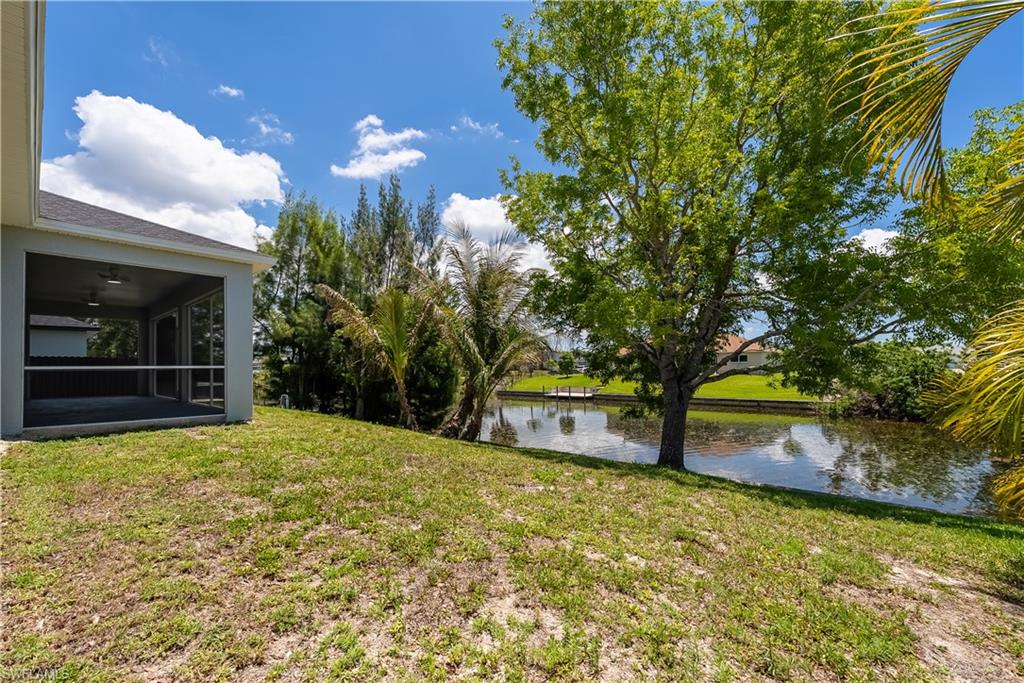 Screened lanai with ceiling fans, offering a waterfront backyard with mature trees and a dock across the canal, add a pool later!