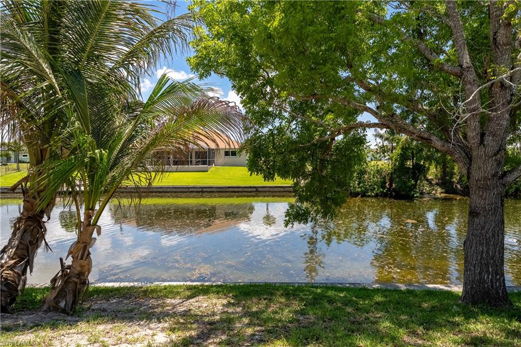 Waterfront property featuring a screened lanai and a manicured lawn