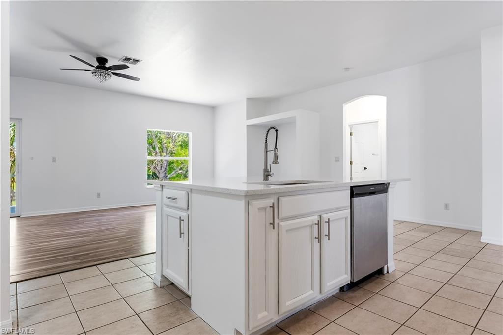 Kitchen island featuring a single-basin sink with a pull-down faucet, white cabinetry, and a built-in stainless steel dishwasher