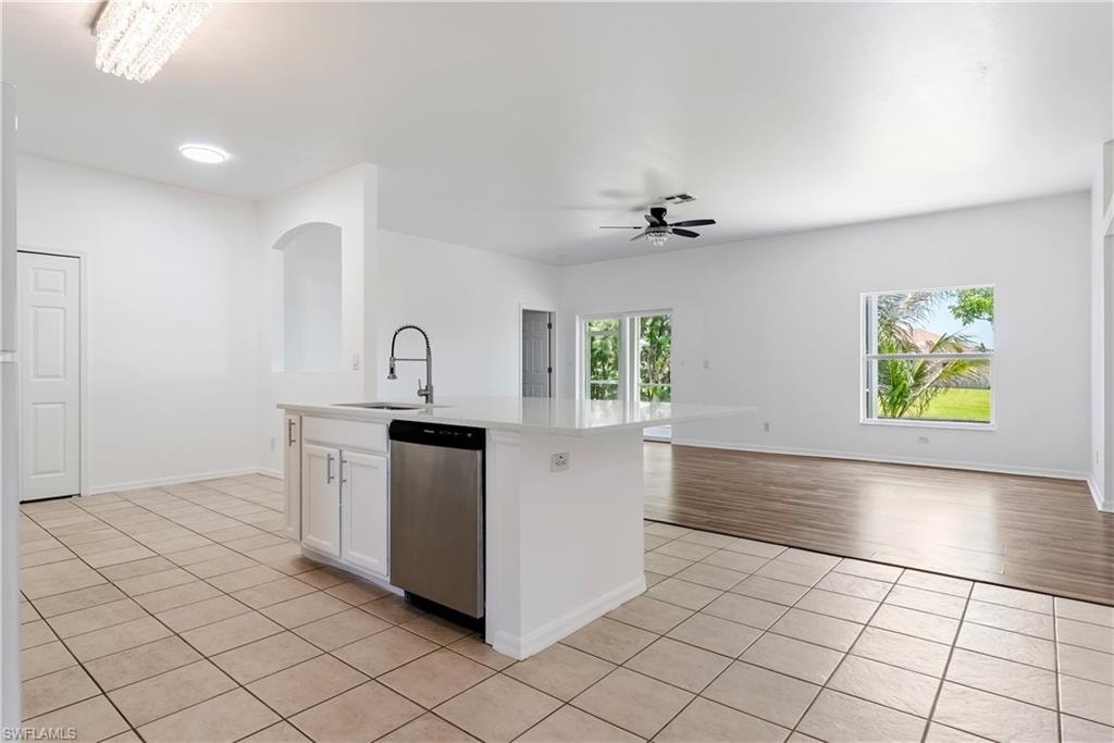 Kitchen island featuring a stainless steel sink with a high-arc faucet, integrated dishwasher, and white cabinetry