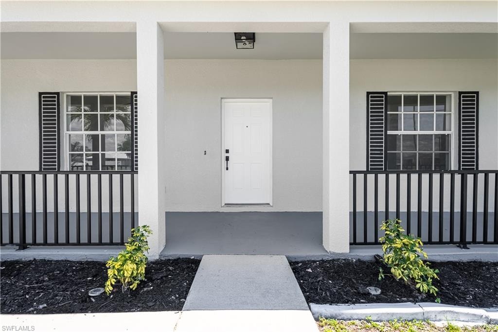 Covered front entrance with a white paneled door, flanked by two multi-pane windows with black louvered shutters