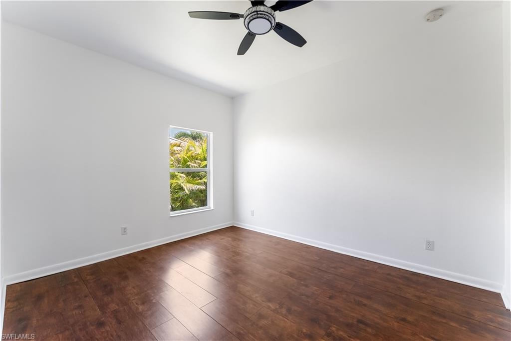 Room featuring wood-finish flooring, white baseboards, a white window frame, and a ceiling fan with black blades