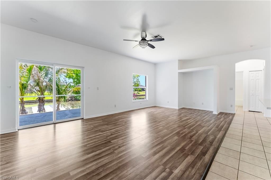 Spacious interior featuring wood-finish flooring, white walls, and a ceiling fan with light fixture