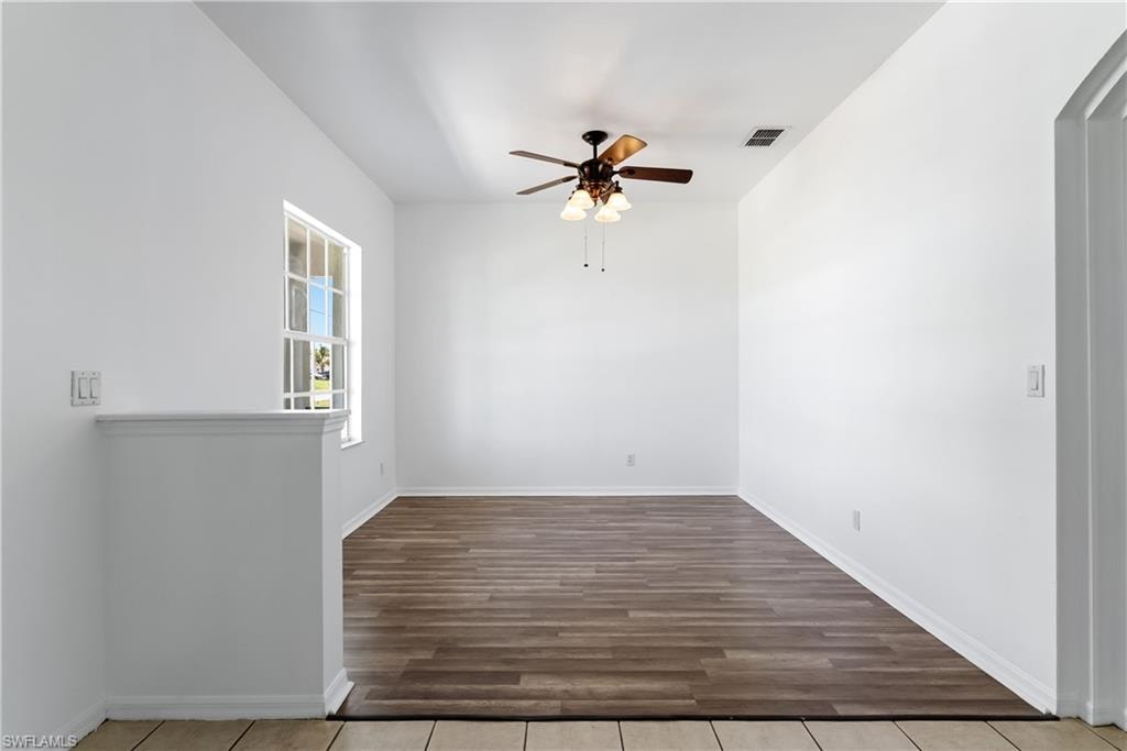 Expansive room featuring wood-finish flooring, white walls, and a ceiling fan with integrated lighting