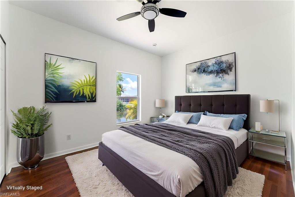 STAGED Bright bedroom featuring rich wood-finish flooring, a contemporary ceiling fan, and a window with a water backdrop