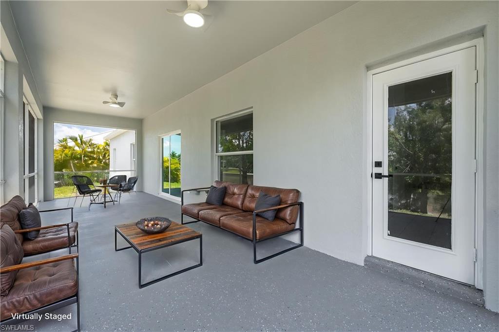 STAGED spacious covered patio featuring a full-light entry door, multiple windows, two ceiling fans, and a speckled gray flooring finish