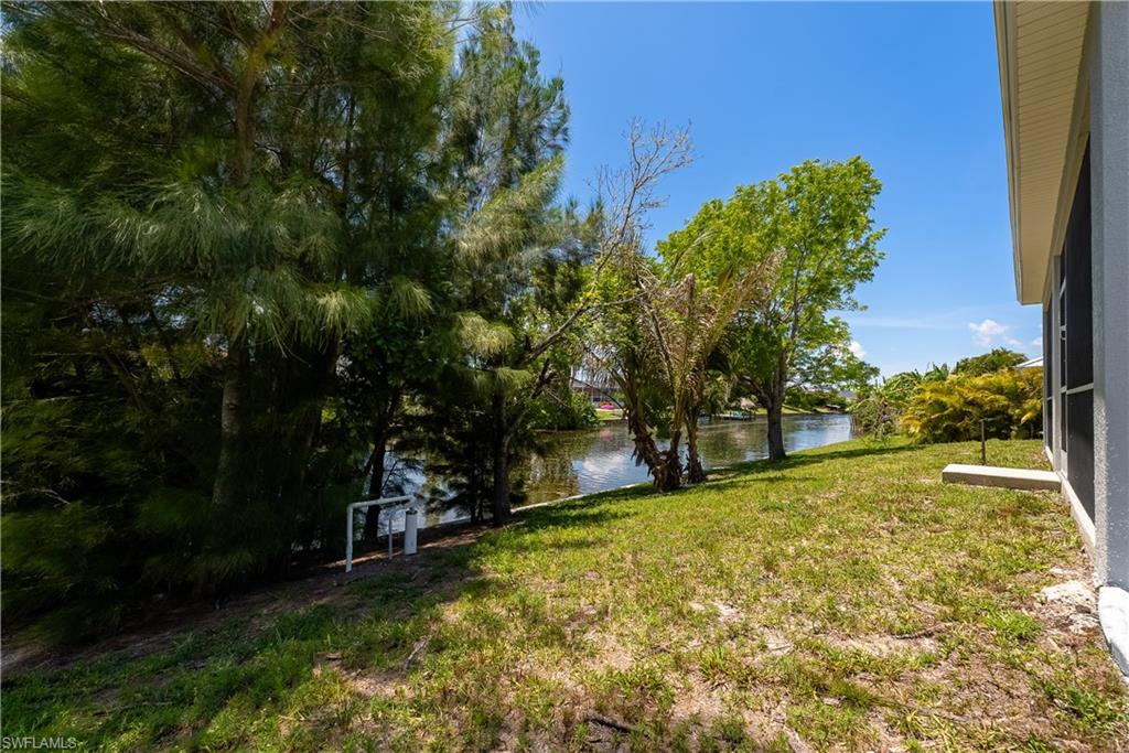 Waterfront setting with direct canal access, featuring mature trees and a grassy expanse