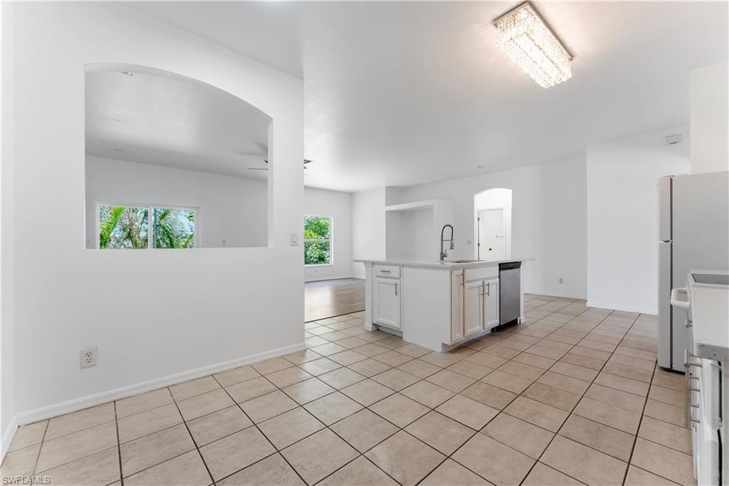 Kitchen featuring a center island, integrated sink with gooseneck faucet, white cabinetry, and stainless steel dishwasher