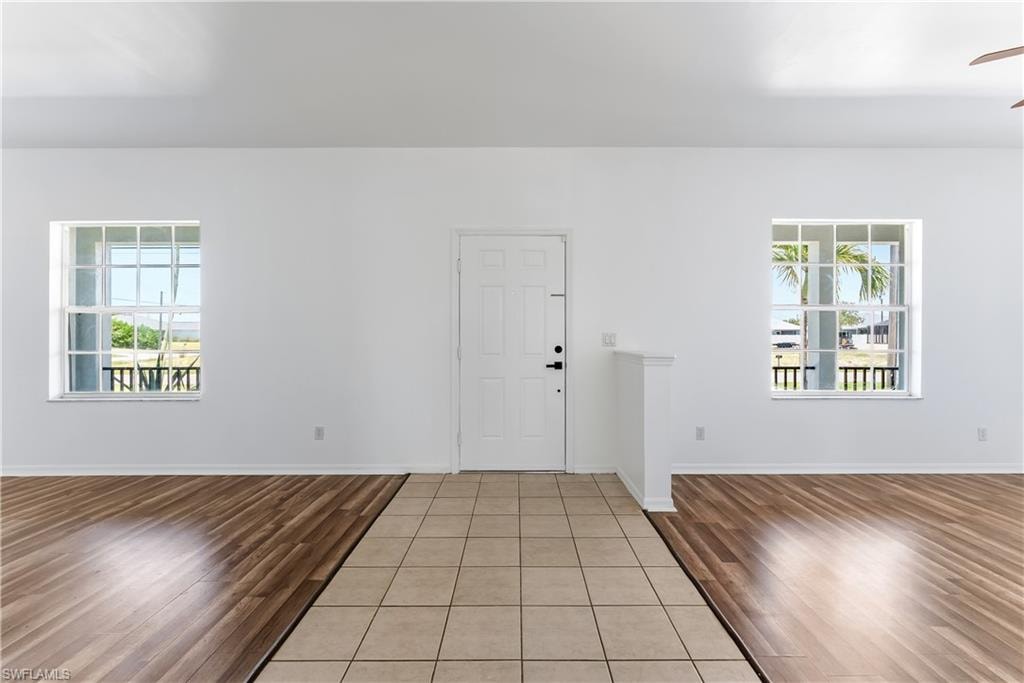 Bright interior space featuring a white entry door, symmetrical paneled windows, and a combination of tile and wood-finish flooring