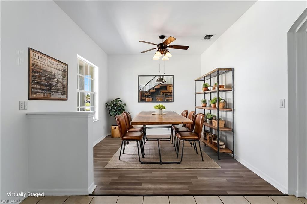 STAGED Dining area featuring wood-finish flooring, a contemporary ceiling fan with integrated lighting, a large window, and a built-in shelving unit