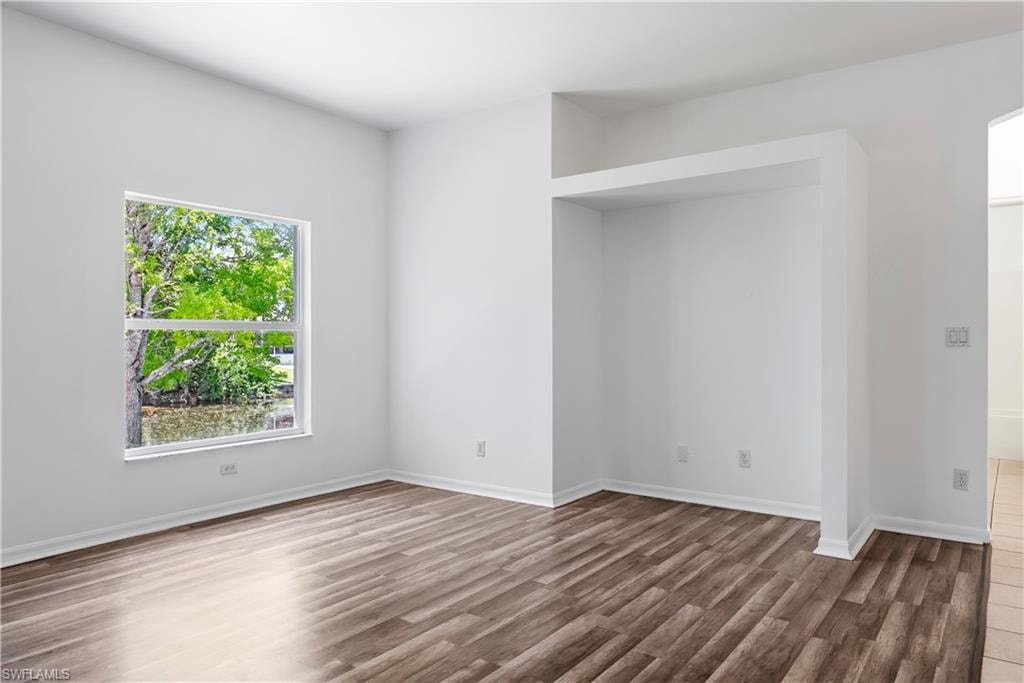 Spacious room featuring wood-finish flooring, a large window, and a built-in architectural niche