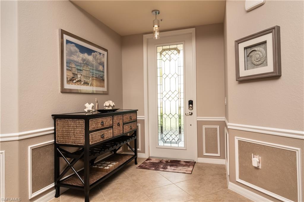 Foyer featuring a leaded glass entry door, decorative wainscoting, and large format tile flooring