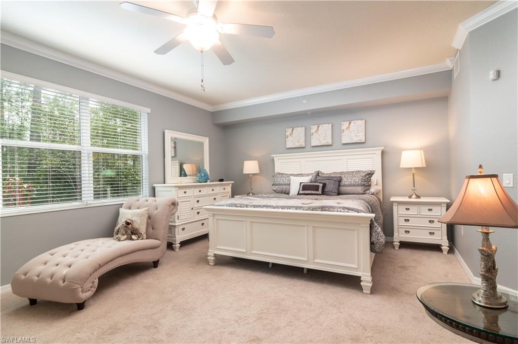 Carpeted bedroom with a large window, crown molding, and a ceiling fan