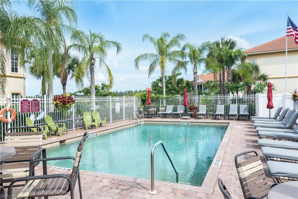 Community pool with a brick paver deck and surrounded by palm trees