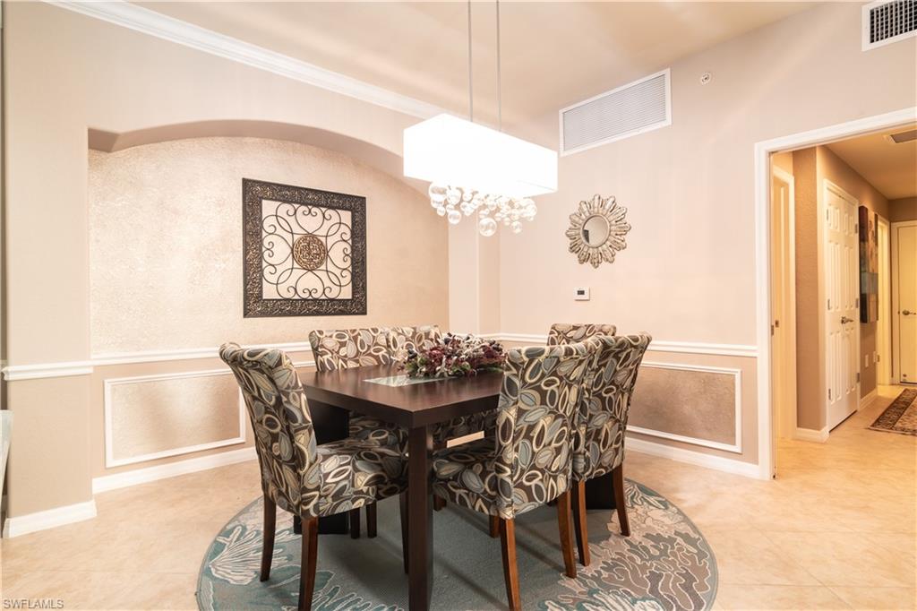Dining area featuring crown molding, chair rail, and a recessed archway with textured wall covering