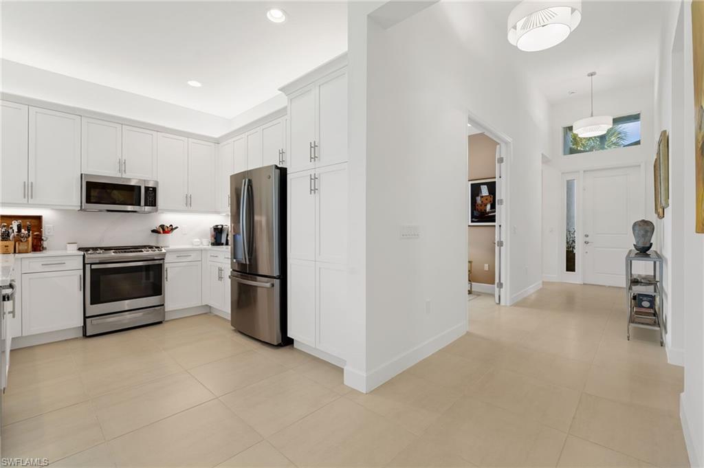 Well- equipped kitchen with stainless steel appliances, quartz countertops & backsplash.