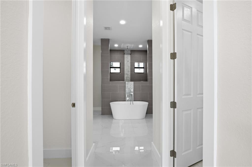 Bathroom with tile walls, a freestanding bath, and recessed lighting