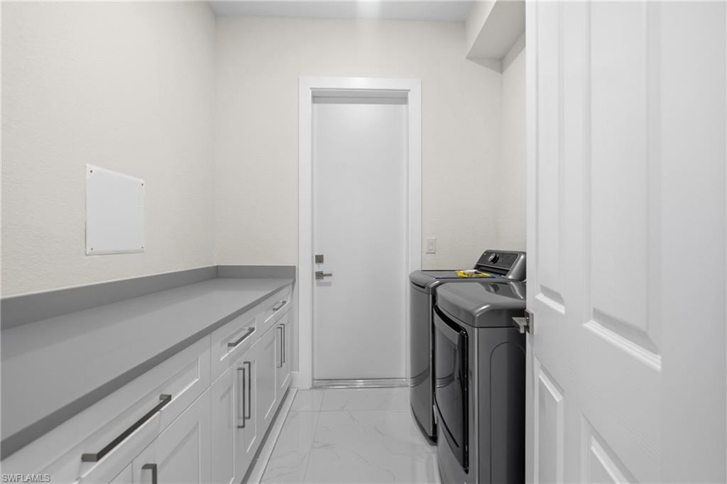 Laundry area with light marble finish flooring and washer and dryer