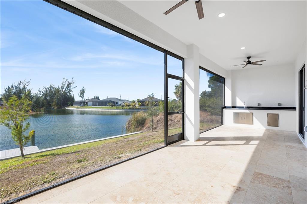 Unfurnished sunroom featuring a ceiling fan, exterior kitchen, and a water view