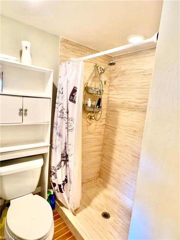 Shower featuring light-toned, horizontally textured tile walls and a matching tile floor
