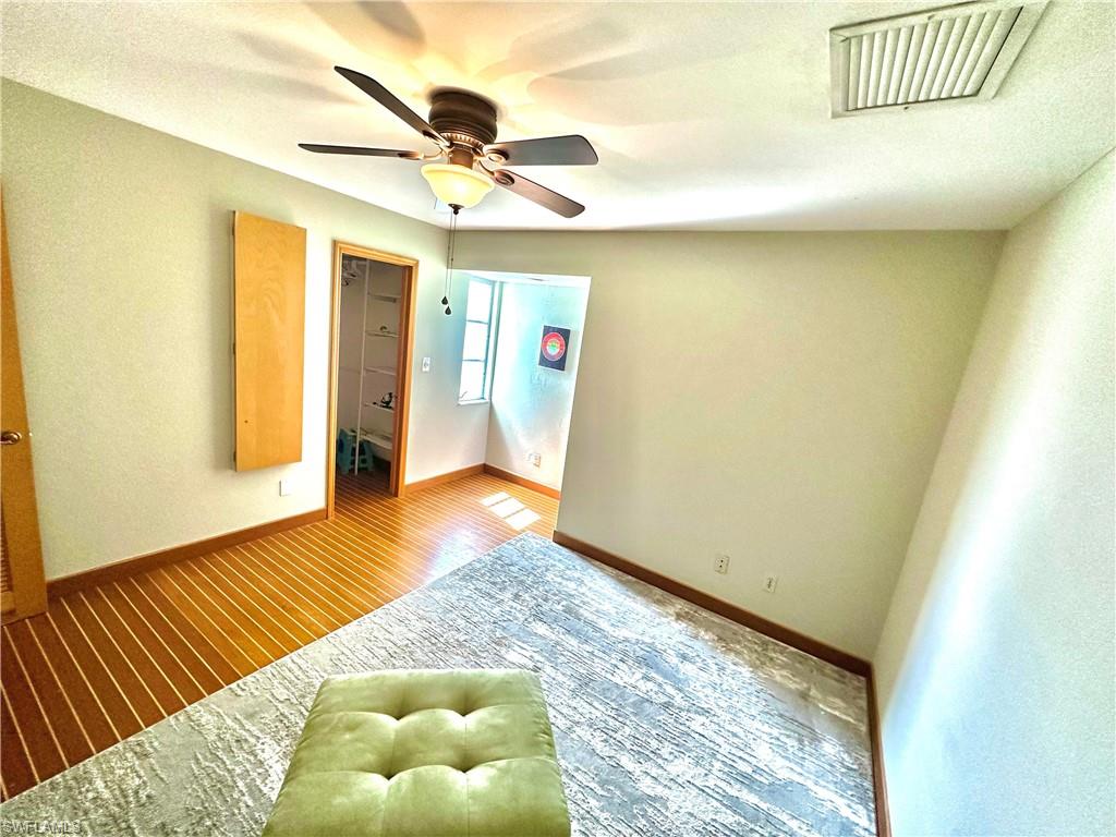 Room featuring wood-finish flooring, a ceiling fan with integrated lighting, and light-toned wall paint