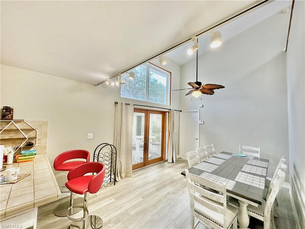 Vaulted ceiling interior featuring track lighting, wood-finish flooring, and a ceiling fan with integrated light