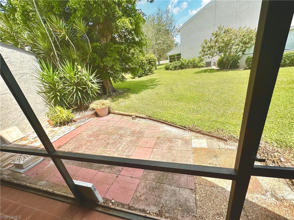 Screened patio featuring terra cotta-toned pavers, an expansive lawn, and mature landscaping