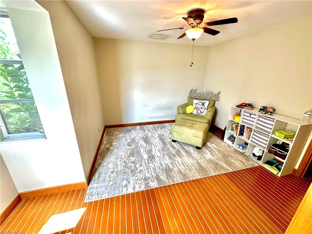 Hardwood flooring with a distinctive plank pattern, neutral wall tones, and an angled window providing natural illumination