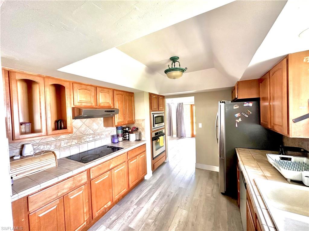 Kitchen featuring wood-finish cabinetry, tile countertops, and a built-in cooktop