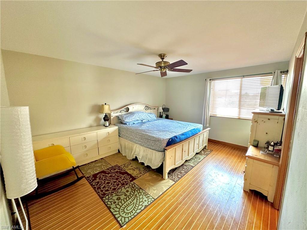 Bedroom featuring wood-finish flooring, a ceiling fan, and a window with horizontal blinds