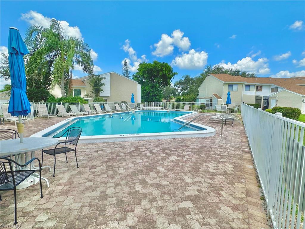 Community swimming pool with a surrounding paver patio and white fencing