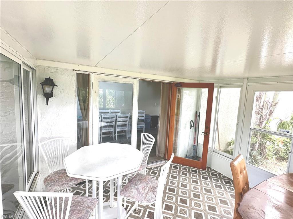 Enclosed patio featuring patterned floor tiling, an exterior wall sconce, and multiple windows