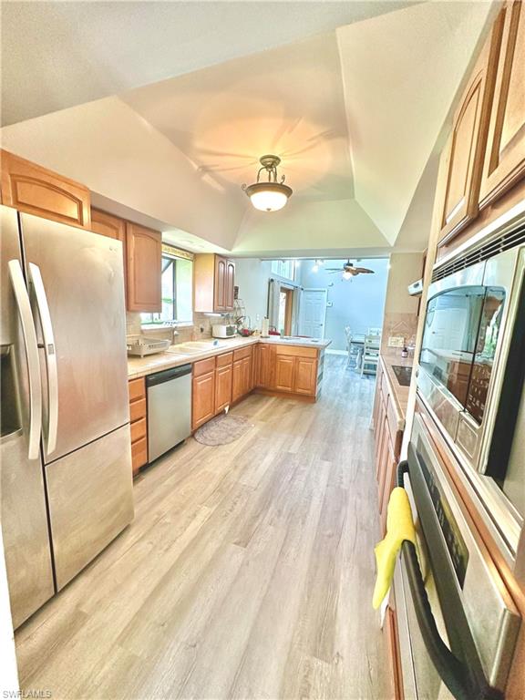 Spacious kitchen featuring light wood-finish cabinetry, stainless steel appliances, light-toned countertops, and wood-finish flooring