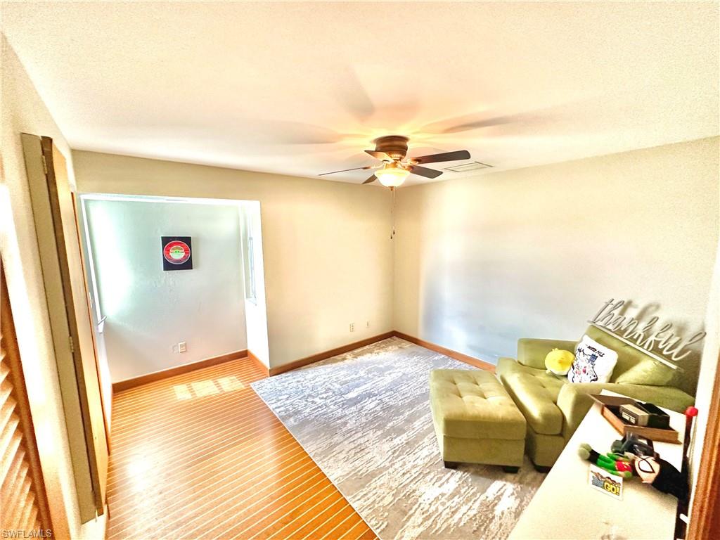 Room featuring wood-finish flooring and a ceiling fan with integrated lighting