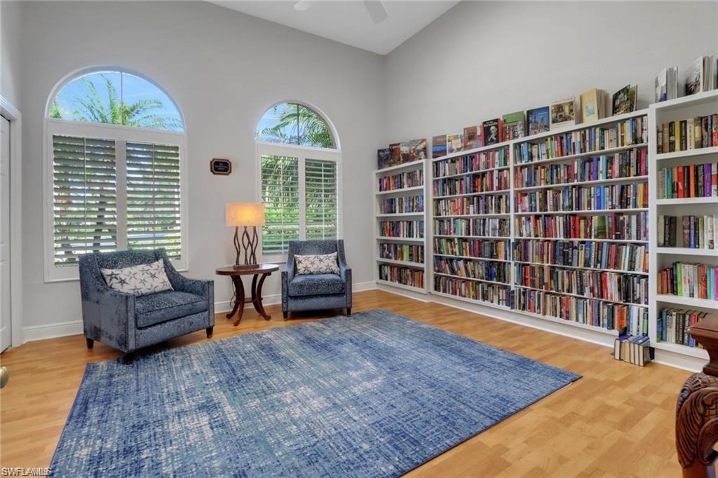 Room featuring extensive built-in shelving, vaulted ceilings, and wood-finish flooring