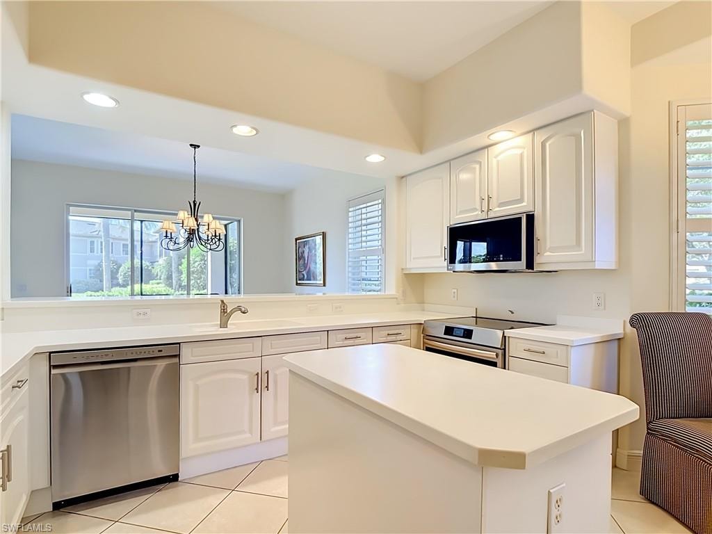 Kitchen featuring white cabinetry, light-toned countertops, tile flooring, and stainless steel appliances including a dishwasher, built-in microwave, and oven