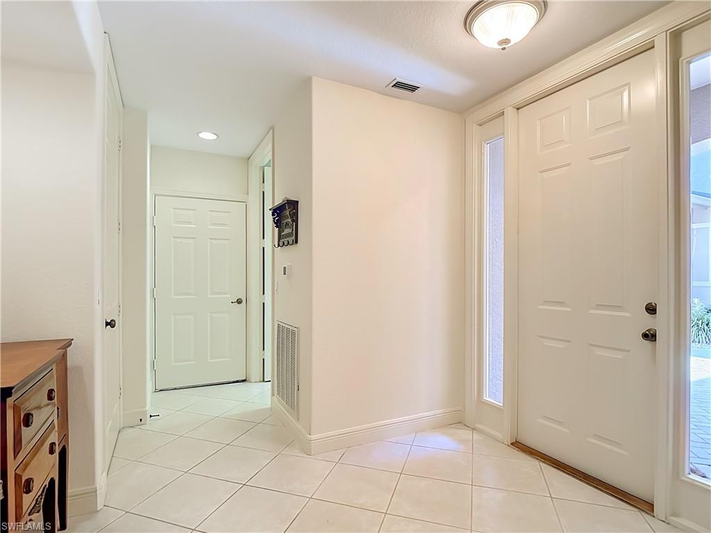 Entryway featuring white paneled doors, sidelight windows, and light-toned tile flooring