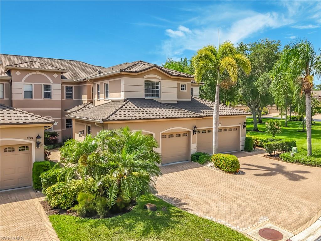 Mediterranean-style exterior featuring a multi-level structure with tiled roofing, neutral stucco finish, multiple two-car garages, and paver driveways
