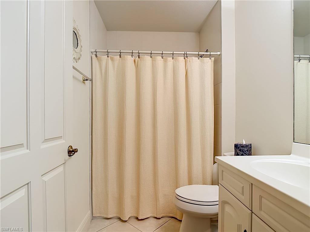 Bathroom featuring a shower-tub combination with tile surround, a white toilet, and a vanity with an integrated sink and cabinet storage