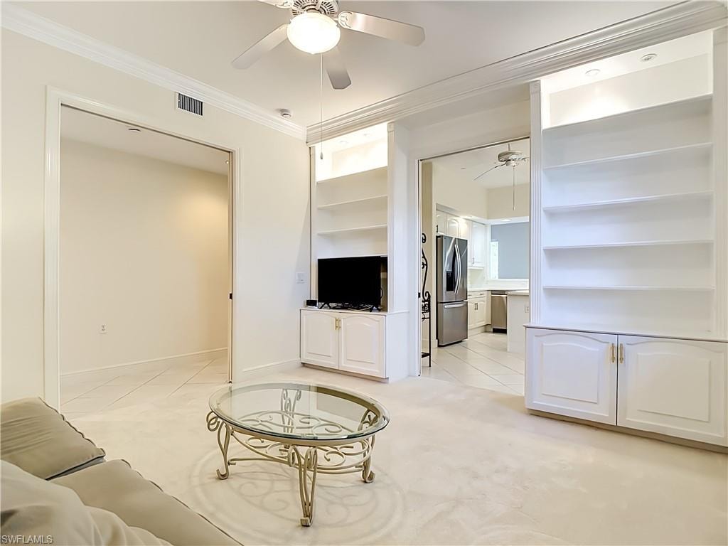 Living area featuring built-in shelving with integrated lighting and lower cabinetry