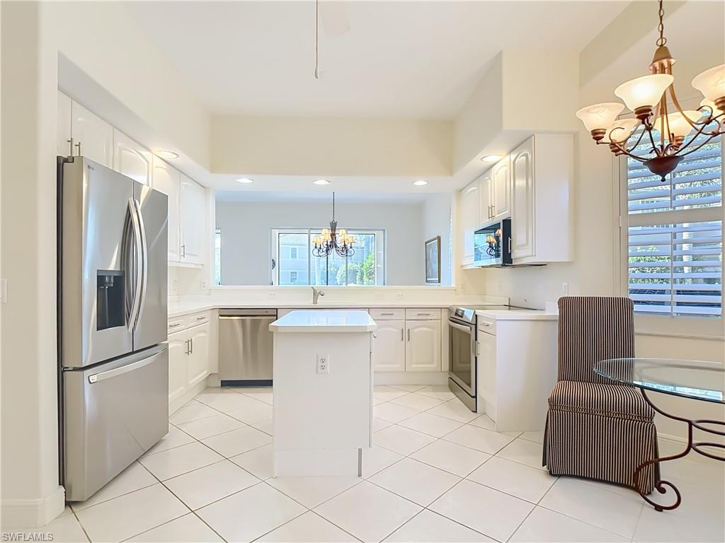 Bright kitchen featuring white cabinetry, stainless steel appliances, a central island, and tiled flooring