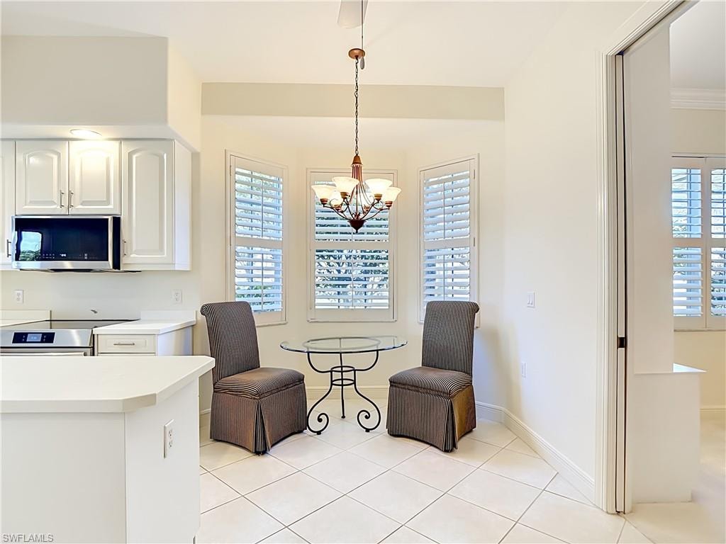 Kitchen with white cabinetry, stainless steel microwave, and a breakfast nook featuring bay windows with plantation shutters