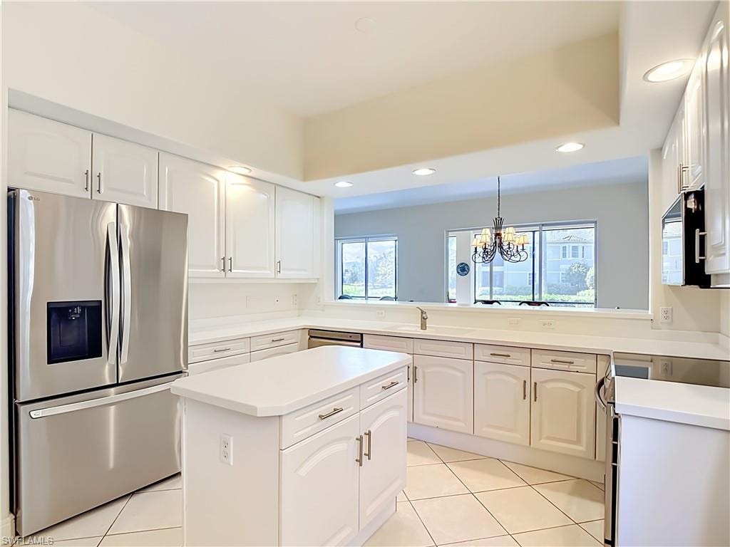 Modern kitchen featuring white cabinetry, light countertops, stainless steel appliances, a center island, and tile flooring