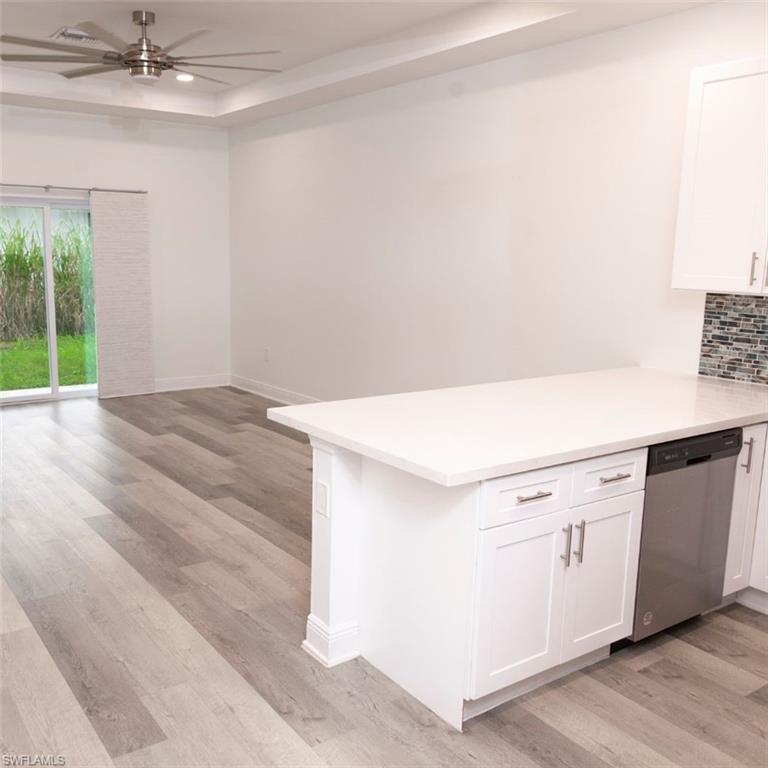 Open-concept living area featuring wood-finish flooring and a tray ceiling